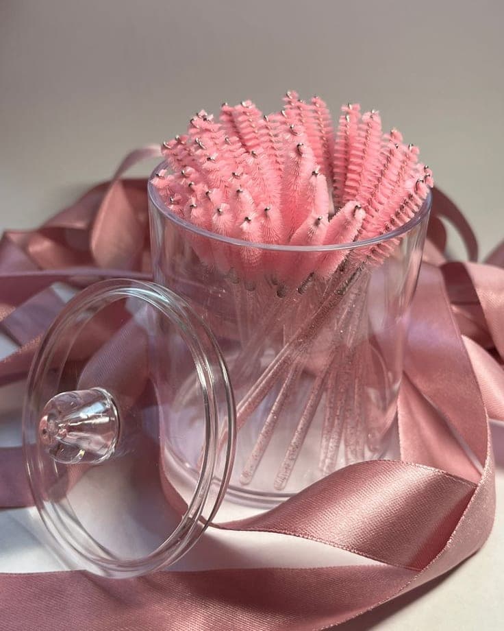 Brossettes à cils roses dans un pot en verre, avec un ruban